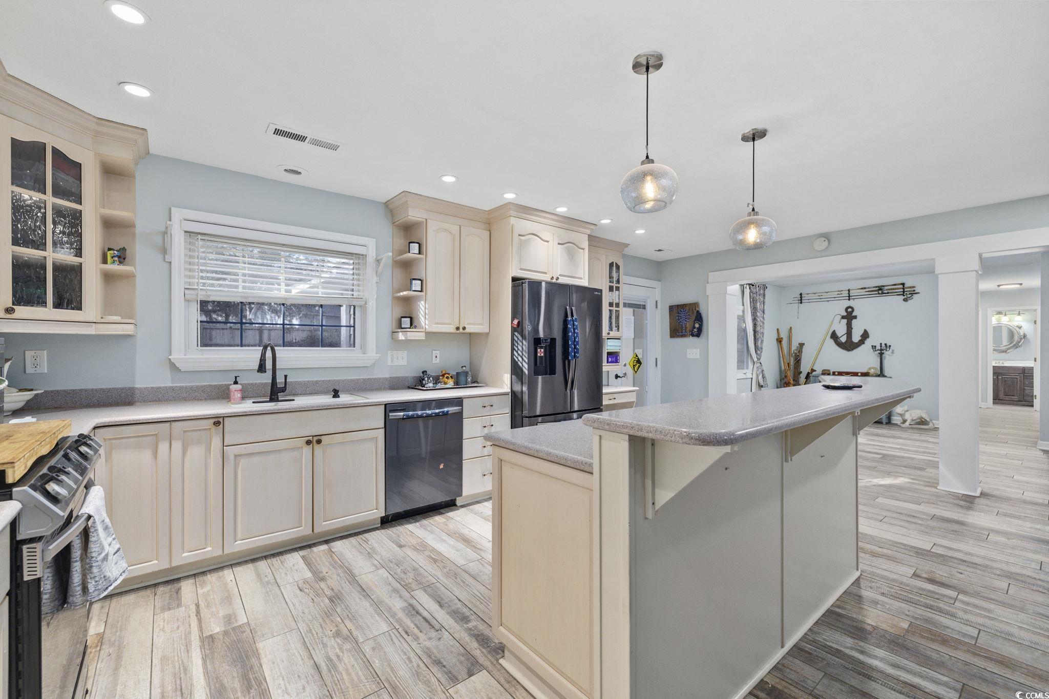 153 Watson Way Pawleys Island, SC 29585 - Photo 10 of 40 Kitchen with open shelves, appliances with stainless steel finishes, a center island, decorative light fixtures, and light wood-type flooring
