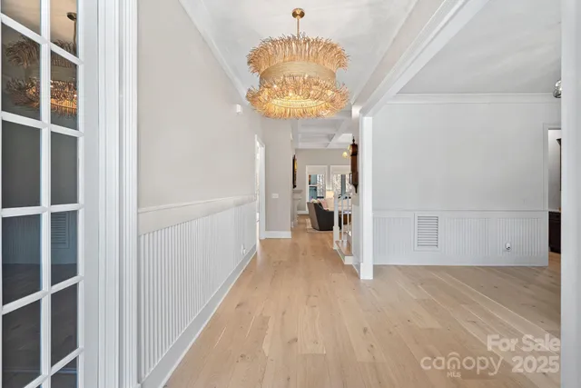 a view of a hallway with wooden floor and a chandelier
