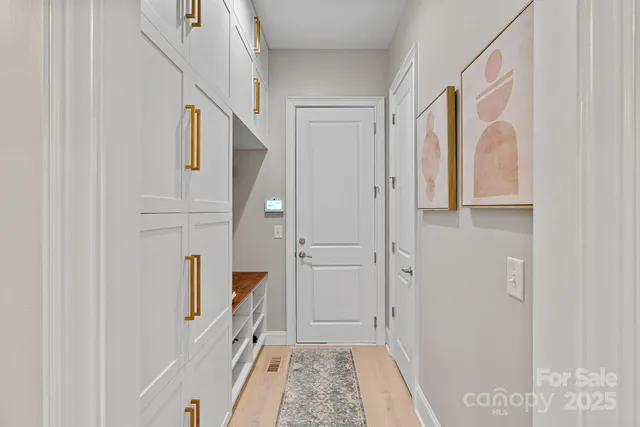 a hallway with white cabinets and wooden floor