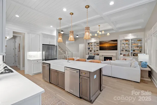 a large white kitchen with a refrigerator a stove top oven a sink a dining table and chairs