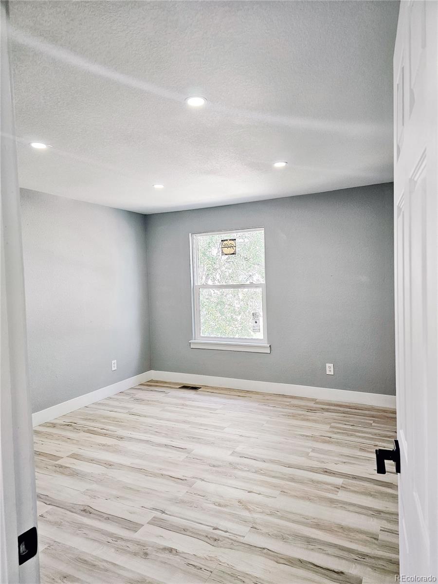 4716 Freeport Way Denver, CO 80239 - Photo 15 of 29 a view of an empty room with wooden floor and a window