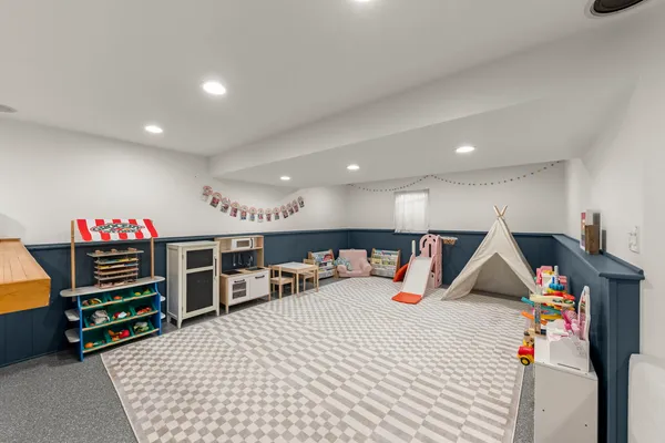 a room with lots of white furniture a chandelier and a wooden floor