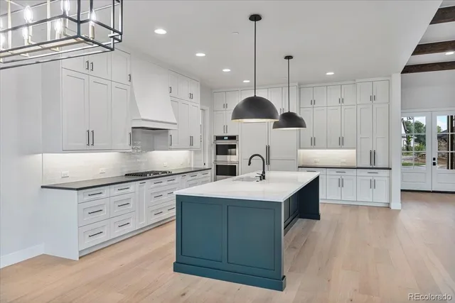 a large kitchen with stainless steel appliances kitchen island granite countertop a sink a stove and a wooden floors