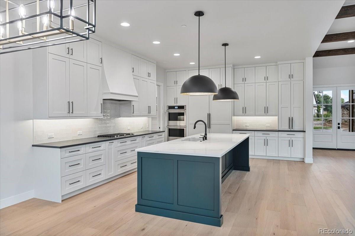 14455 Anvil Way Golden, CO 80403 - Photo 5 of 35 a large kitchen with stainless steel appliances kitchen island granite countertop a sink a stove and a wooden floors