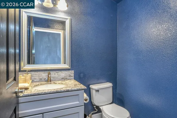 a bathroom with a granite countertop toilet and a sink