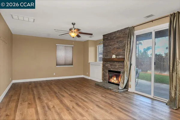 a view of an empty room with wooden floor fireplace and a window
