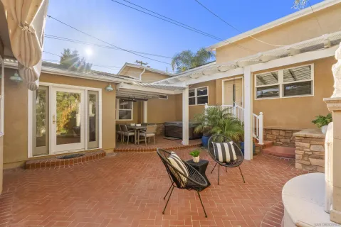 a view of a patio with table and chairs potted plants and floor to ceiling window