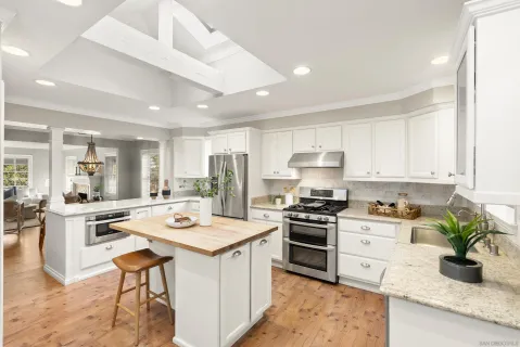a kitchen with a stove a sink a refrigerator and white cabinets with wooden floor