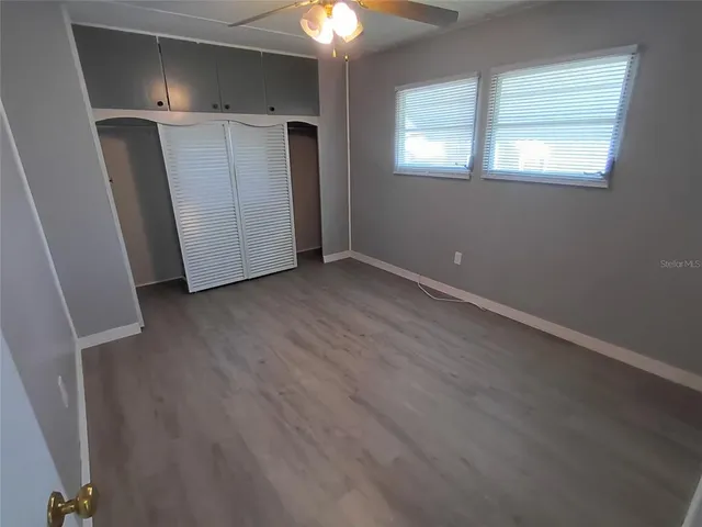 an empty room with wooden floor cabinet and windows