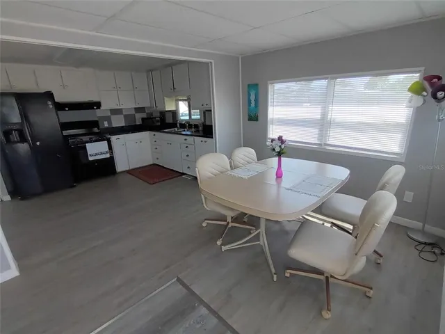 a kitchen with a dining table chairs and refrigerator