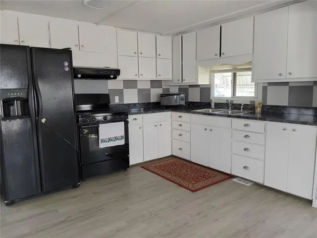 a kitchen with granite countertop white cabinets and stainless steel appliances