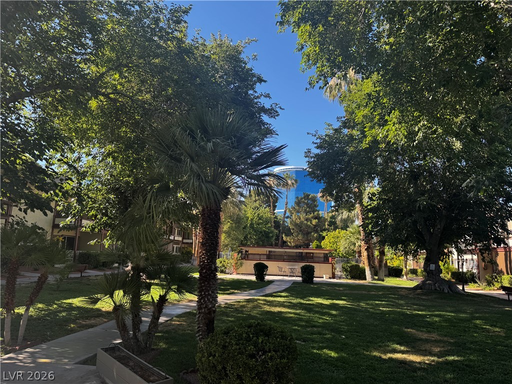 350 East Desert Inn Road, Unit C103 Las Vegas, NV 89109 - Photo 15 of 23 Lush landscaping and mature trees frame a central lawn, creating a serene communal oasis.