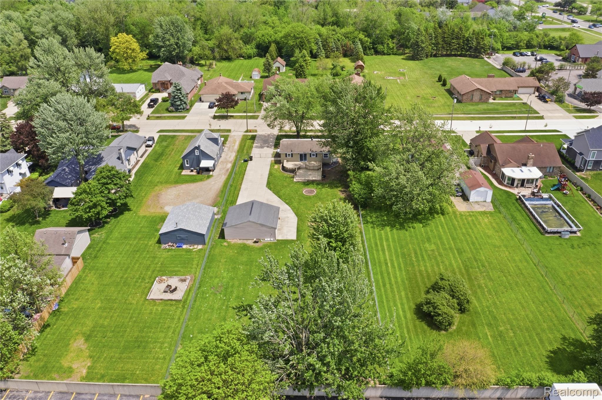 37257 Dundee Street Sterling Heights, MI 48310 - Photo 46 of 47 Expansive property featuring a detached garage, a secondary outbuilding, a concrete driveway, a dedicated fire pit area, and mature landscaping