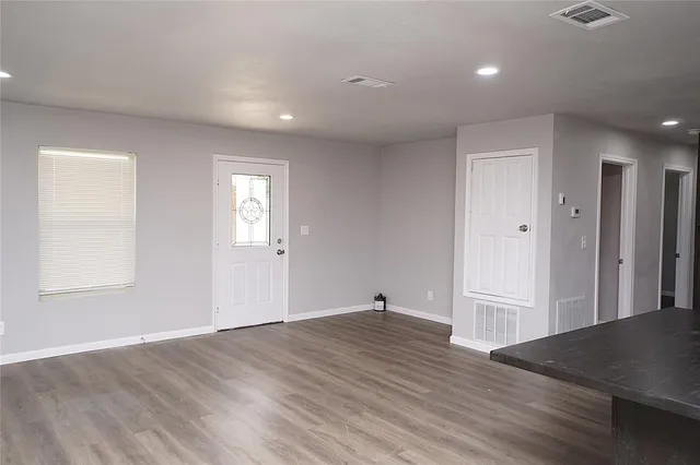 an empty room with wooden floor and windows