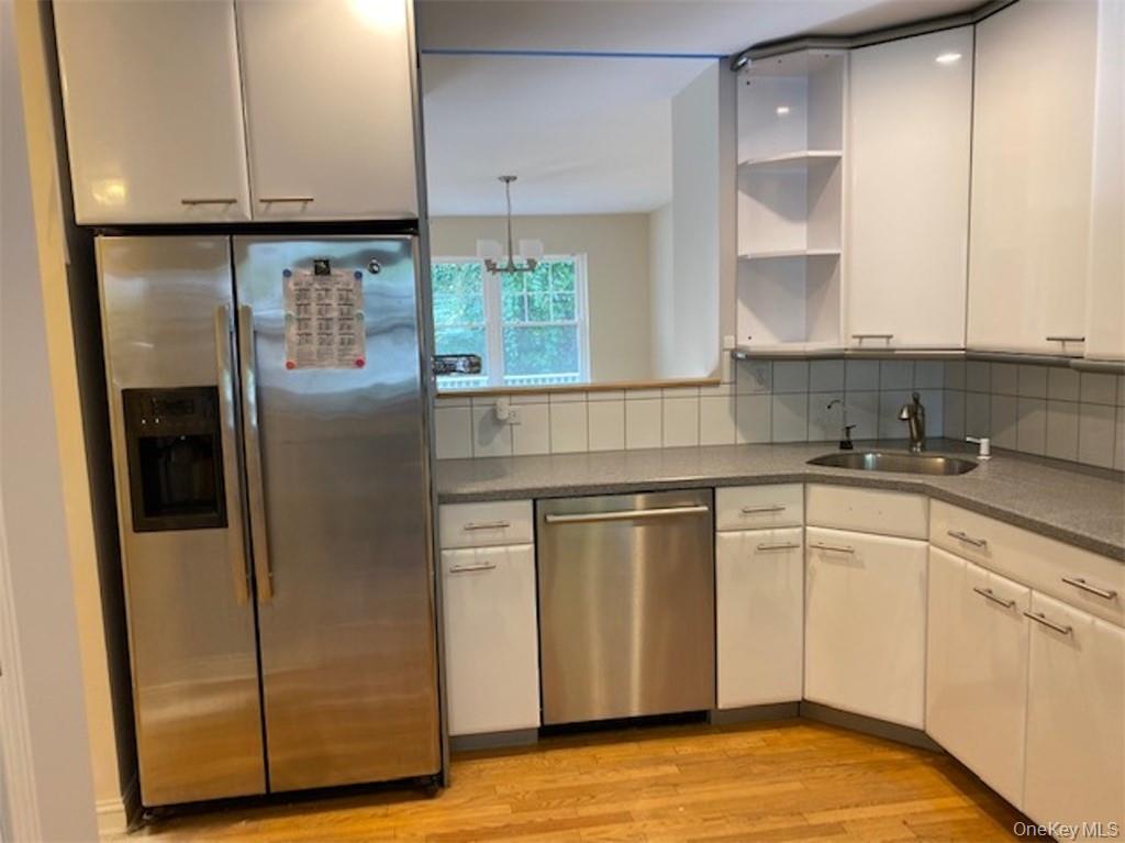 51 Winding Ridge Road White Plains, NY 10603 - Photo 7 of 30 a kitchen with stainless steel appliances granite countertop a refrigerator a sink and white cabinets with wooden floor
