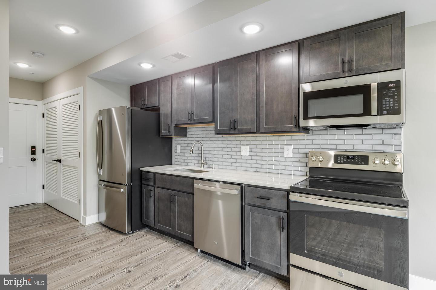 1617 Rhode Island Avenue Northeast, Unit 102 Washington, DC 20018 - Photo 3 of 17 a kitchen with granite countertop wooden cabinets a stainless steel appliances and wooden floor