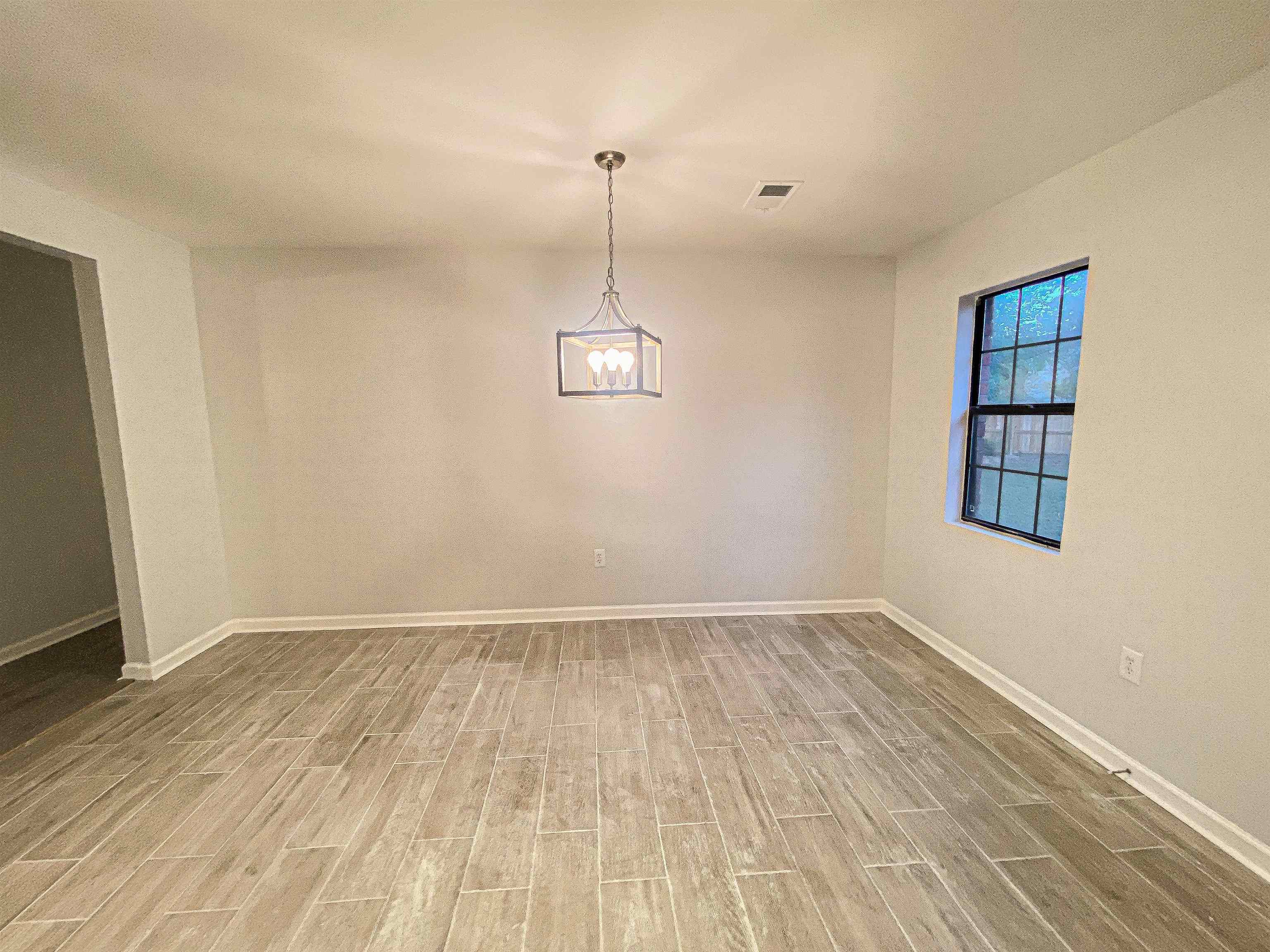 157 Pickett Road Memphis, TN 38109 - Photo 6 of 24 a view of an empty room with wooden floor and a window