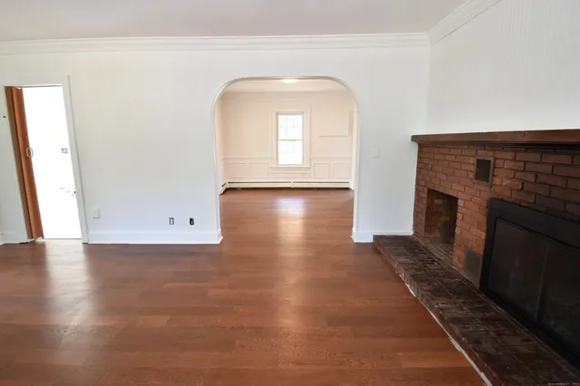 an empty room with wooden floor and a fireplace