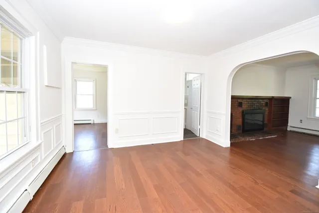a view of empty room with wooden floor and fireplace