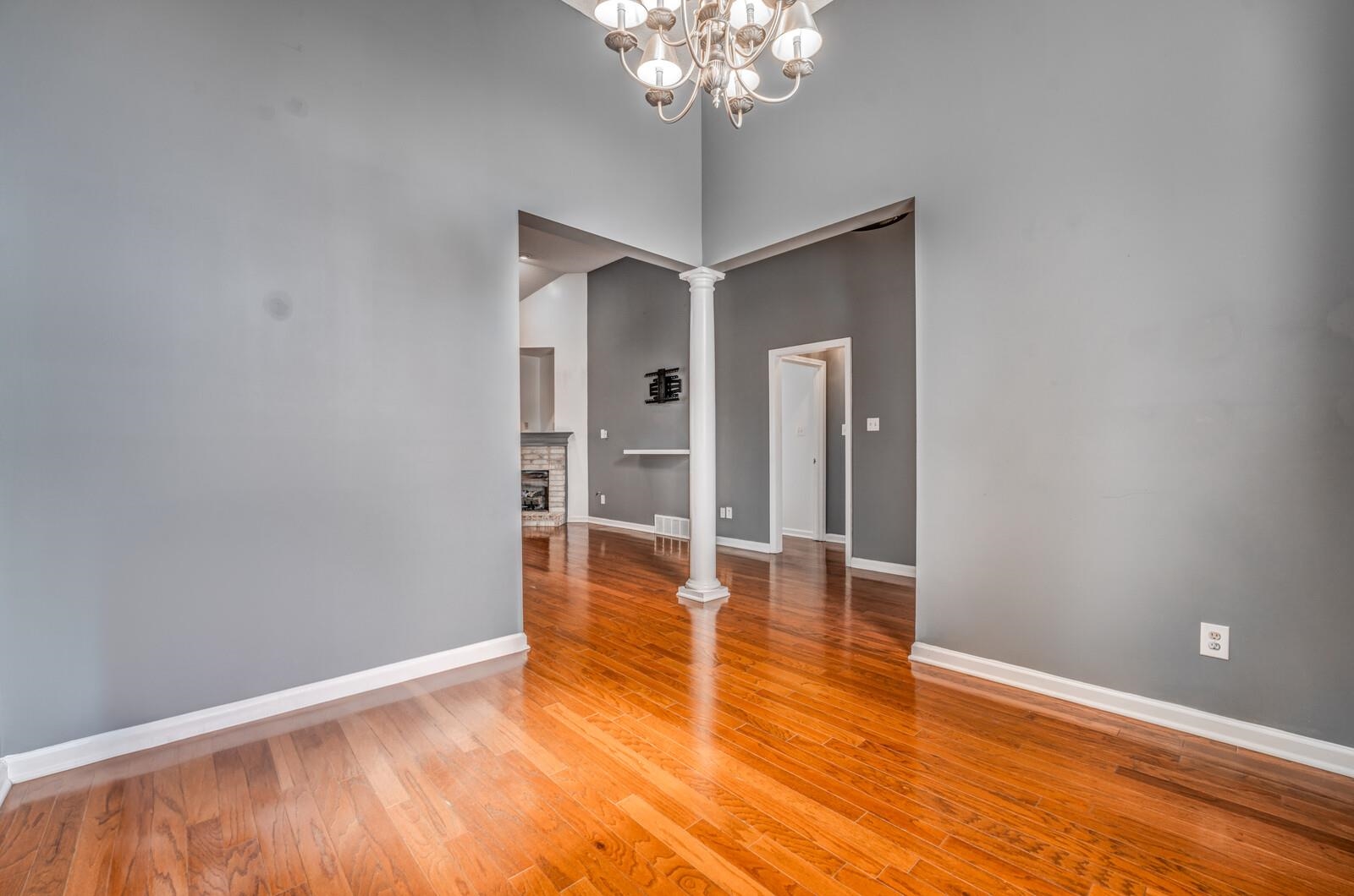 8574 Thor Road Memphis, TN 38018 - Photo 8 of 40 Unfurnished dining area with baseboards, ornate columns, light wood finished floors, a fireplace with raised hearth, and a towering ceiling