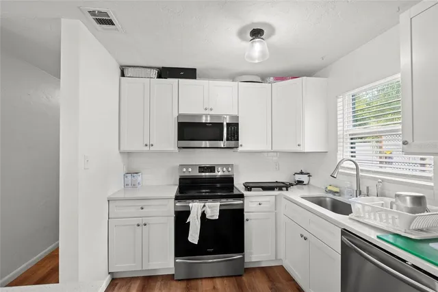 a kitchen with white cabinets stainless steel appliances and sink