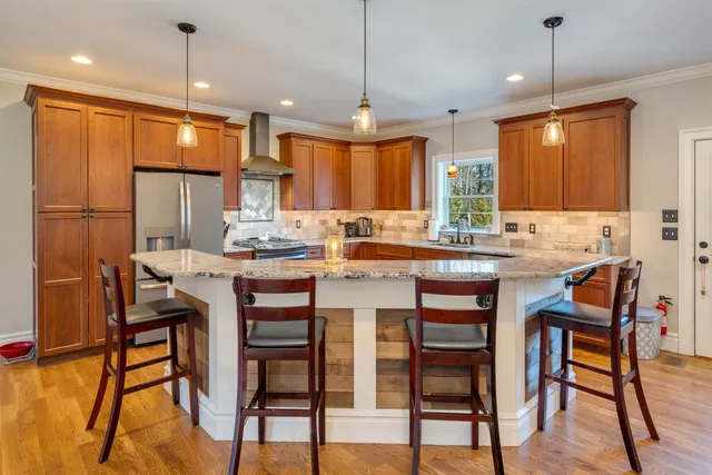 a large kitchen with stainless steel appliances granite countertop a lot of counter space and wooden floors