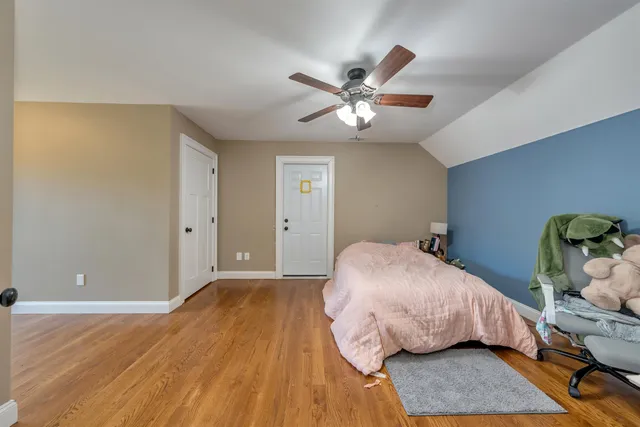 a bedroom with wooden floor ceiling fan and window