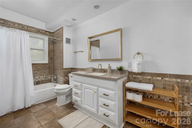 a bathroom with a granite countertop toilet sink and mirror