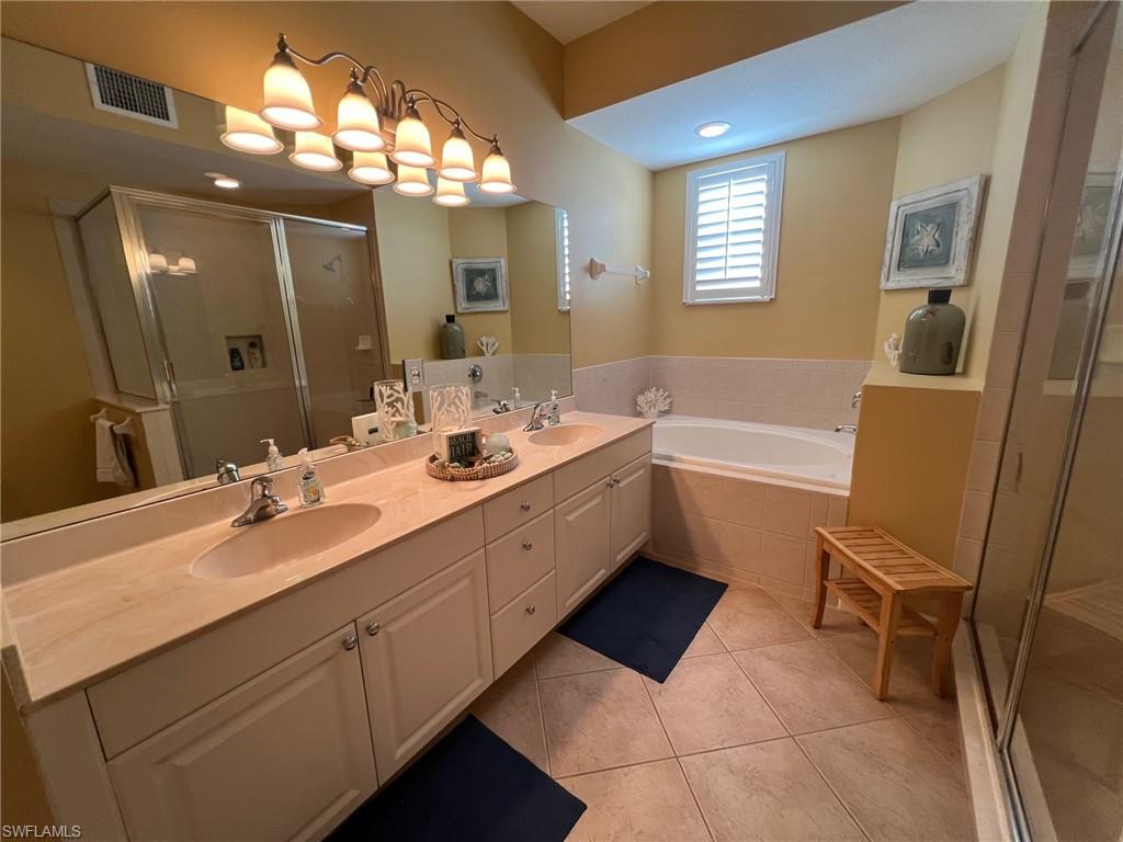 6864 Ascot Drive, Unit 101 Naples, FL 34113 - Photo 17 of 40 a spacious bathroom with a double vanity sink a mirror and a bathtub