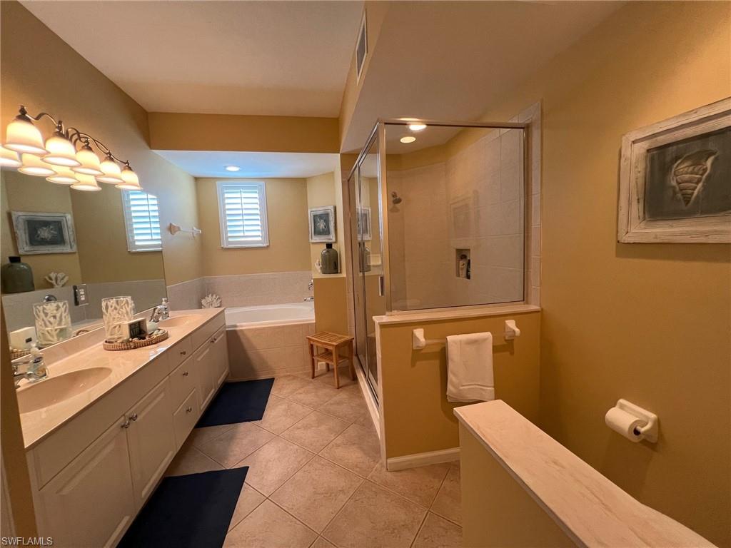 6864 Ascot Drive, Unit 101 Naples, FL 34113 - Photo 18 of 40 a bathroom with a double vanity sink toilet mirror and bathtub