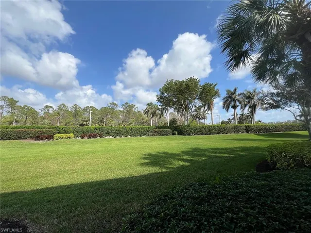 a view of a white house with a large tree and plants