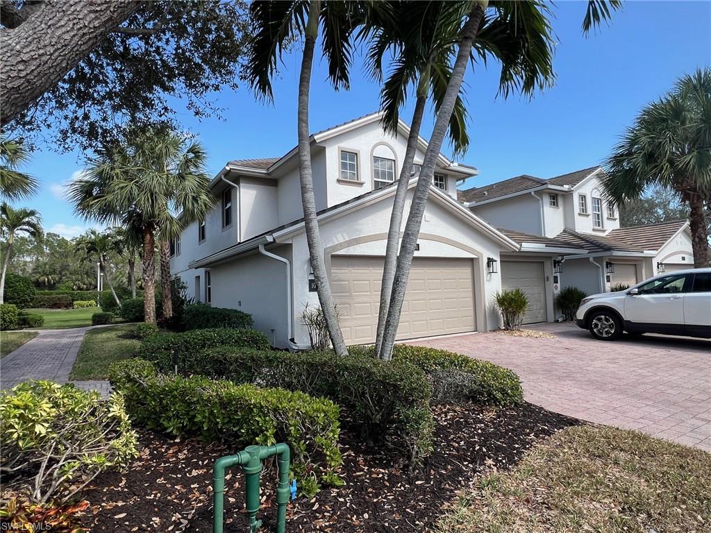 6864 Ascot Drive, Unit 101 Naples, FL 34113 - Photo 4 of 40 a view of a white house with a large tree and plants