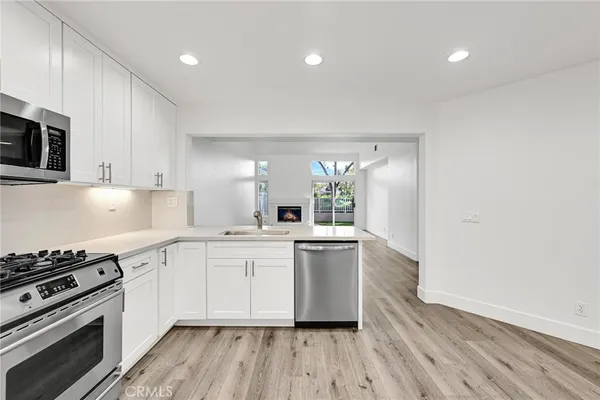 a kitchen with cabinets wooden floor and stainless steel appliances