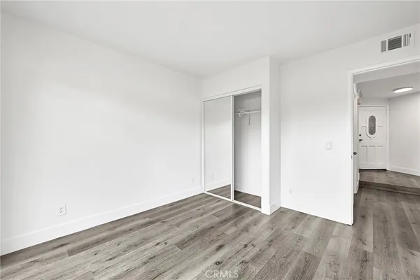 an empty room with wooden floor & windows