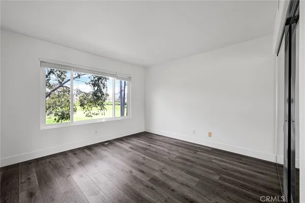 an empty room with wooden floor and window