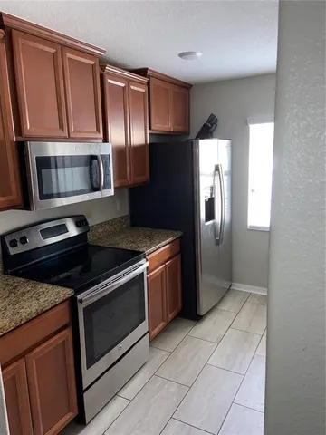 a kitchen with granite countertop a refrigerator and a stove top oven