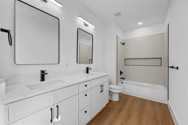 a bathroom with a double vanity sink toilet mirror and bathtub