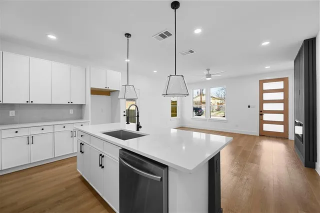 a kitchen with stainless steel appliances granite countertop a sink a center island and a wooden floor