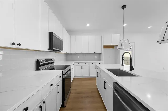 a kitchen with white cabinets sink and stainless steel appliances