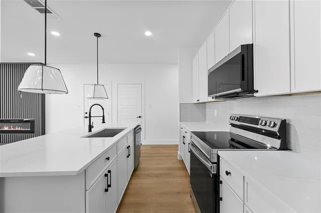 a kitchen with stainless steel appliances a sink a stove and a wooden floor