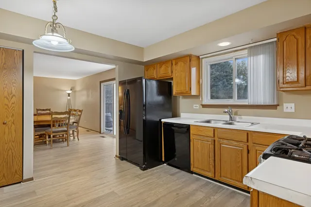 a kitchen with stainless steel appliances granite countertop a refrigerator a sink a stove and island with wooden floor