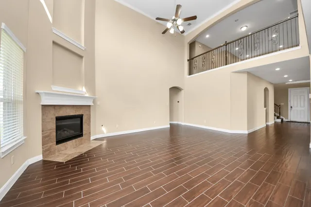 a view of a livingroom with a fireplace a ceiling fan and wooden floor