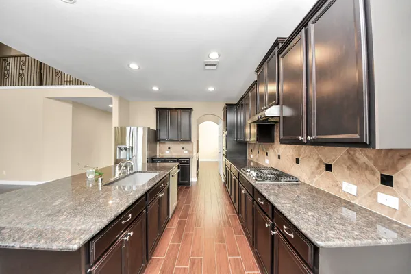 a kitchen with stainless steel appliances granite countertop a sink a stove and a refrigerator