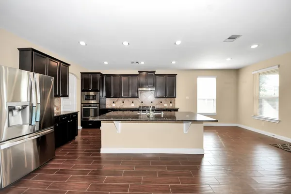 a large kitchen with stainless steel appliances granite countertop a large counter top a stove a sink and a refrigerator