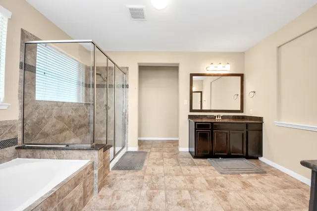 a spacious bathroom with a granite countertop tub sink and mirror