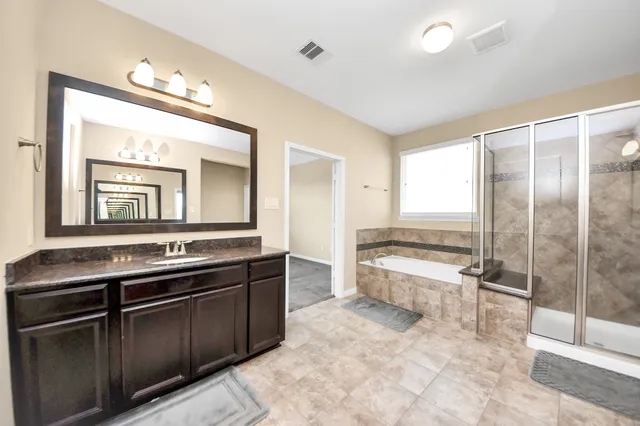 a spacious bathroom with a granite countertop sink a toilet a mirror and bathtub