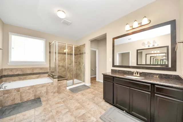 a spacious bathroom with a tub a sink and a large mirror