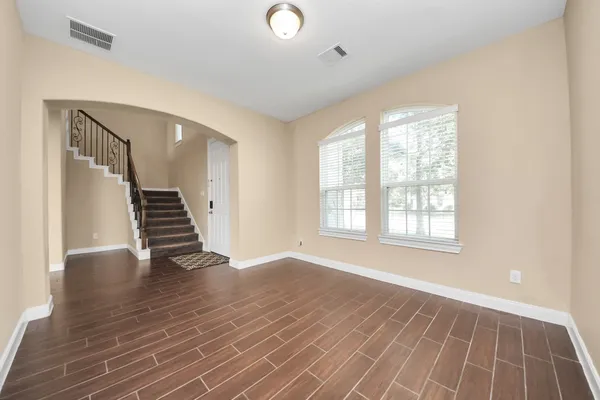 an empty room with wooden floor and windows