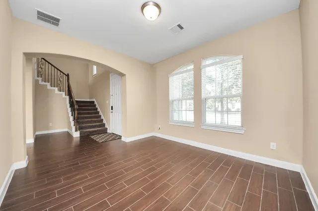 an empty room with wooden floor and windows