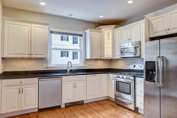 42 Lagrange Street, Unit 1 Boston, MA 02132 - Photo 8 of 29 a kitchen with cabinets stainless steel appliances a sink and wooden floor